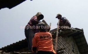 BANTU WARGA : Personil BPBD Pemkab Tuiban saat membantu memperbaiki atap rumah warga yang rusak