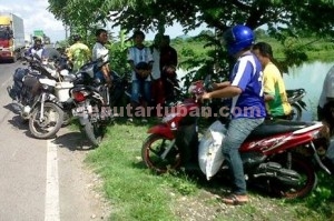 AMBIL UNTUNG : Sejumlah warga mengambil pakan udang muatan truk tronton yang tumpah