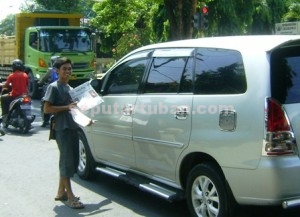 SEMANGAT : Ali Imron saat akan menjual koran kepada pengguna jalan