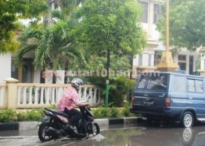 TERGENANG : Pemotor ekstra pelan saat melintasi genangan air di depan Kantor Dinsosnakertran
